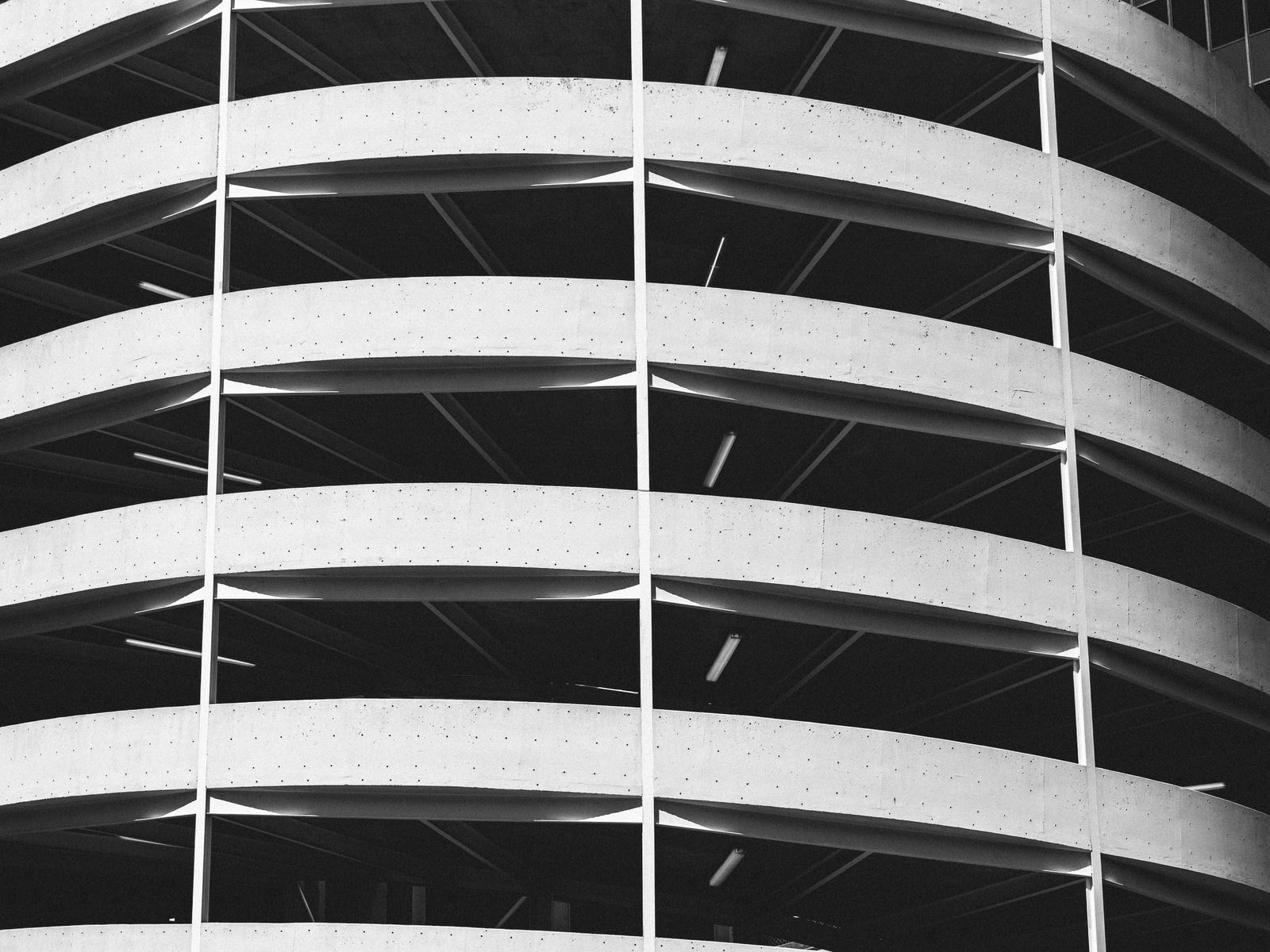 Black-and-white view of the curved concrete floors of a parking garage